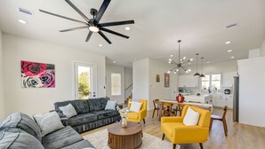 Ein modernes Wohnzimmer mit einer Couch, Sesseln, einem Couchtisch und einem Essbereich mit Stühlen und einem Tisch.