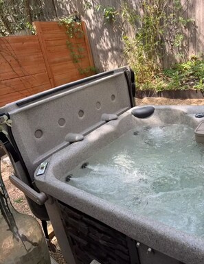 A hot tub with a stone exterior and a wooden fence in the background. - South Congress Luxury Treehouse (Austin)