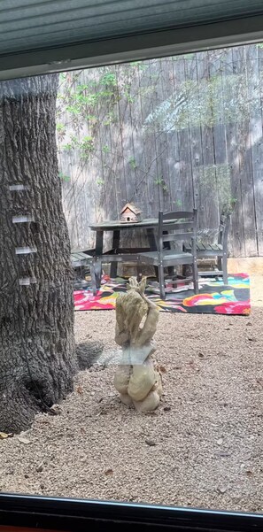 A tree with a birdhouse on a wooden stand, a colorful rug, and a chair. - South Congress Luxury Treehouse (Austin)