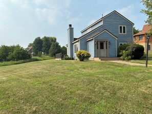 Ein zweistöckiges Haus mit Veranda, Schornstein und einem gepflegten Rasen.