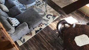 Ein Wohnzimmer mit einer Couch, einem runden Couchtisch, einem Kamin und einem gemusterten Teppich.