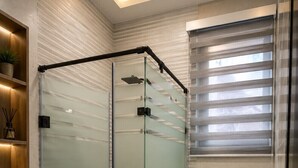 Un baño moderno con ducha envuelta en vidrio, inodoro y tocador con lavamanos.