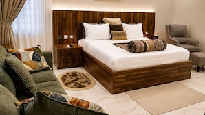 Un dormitorio moderno con una cama grande, un cabecero de madera, un sofá verde, una silla y un ventilador de techo.