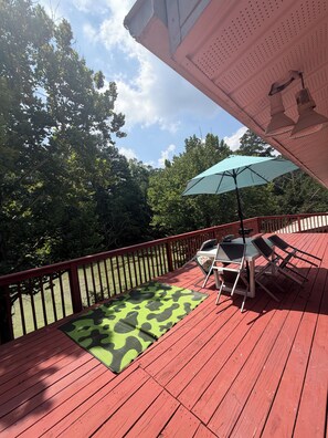 A red deck with a green mat, a table, chairs, and a blue umbrella. - Private Lake House (Covington)