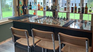 A bar area with a chessboard, bar stools, and a variety of liquor bottles. - Pet friendly Lakefront House with hot tub and large Deck on Summit Lake (Argyle)