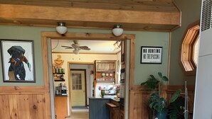 A wooden interior with a dining area, kitchen, and a sign prohibiting hunting and trespassing. - Pet friendly Lakefront House with hot tub and large Deck on Summit Lake (Argyle)