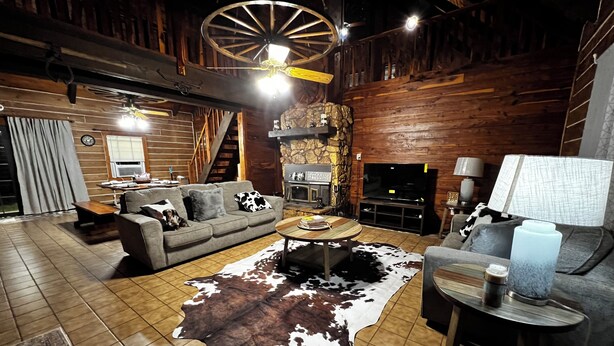 A rustic living room with a sofa, a coffee table, a cowhide rug, a fireplace, and a television.