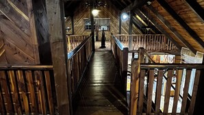 An attic-style room with wooden beams, a wooden staircase, and a view of the upper floor.