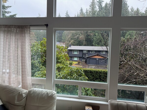 A room with a large window, a sofa, and a small table. - Enjoy a pleasant furnished hotel like suite experience in charming Lynnwood (Lynnwood)
