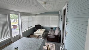 Une véranda abritée avec une table et des chaises, un canapé et un ventilateur de plafond.