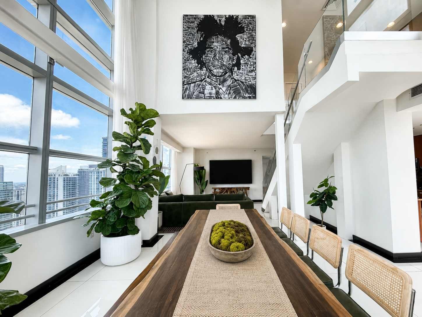 A modern interior with a dining area, large windows, and a city view.