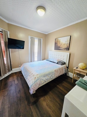 A bedroom with a bed, a television, a painting, and a small table with a lamp. - Spacious room with private bathroom in Federal Hill near Downtown (Providence)