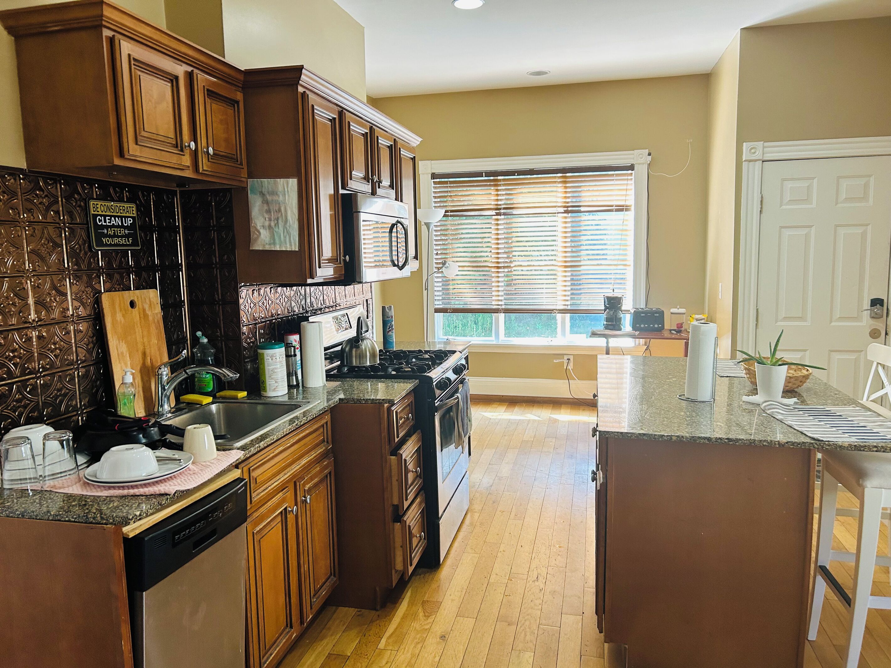 A kitchen with wooden cabinets, a stove, and a window with blinds.