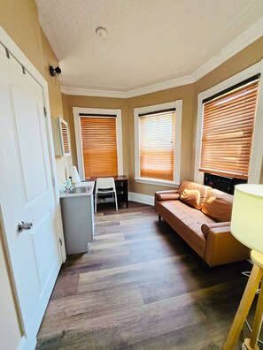 Ein kompakter Wohnraum mit Küchenzeile, Essbereich und einer Sitzecke mit Sofa und Lampe.