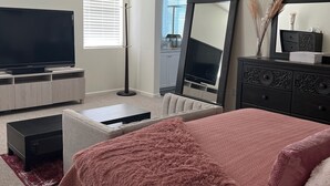 A bedroom with a bed, TV, dresser, and a large mirror.