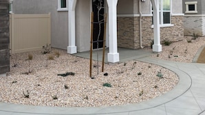 A two-story house with a covered porch, a stone facade, and a gravel driveway.