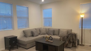A living room with a sectional sofa, a coffee table, a lamp, and a cabinet.