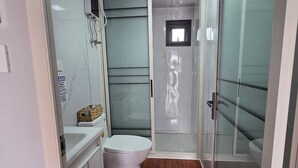 Ein kleines Badezimmer mit Toilette, Duschkabine und Waschtisch.