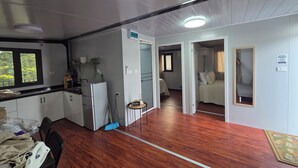 Ein kompaktes Hotelzimmer mit Küchenzeile, Essbereich und kleinem Badezimmer.