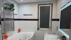 A modern bathroom with a bathtub, a sink, a mirror, and a window. - Spacious & lovely apartment available in Rødovre, CPH. (Rødovre)