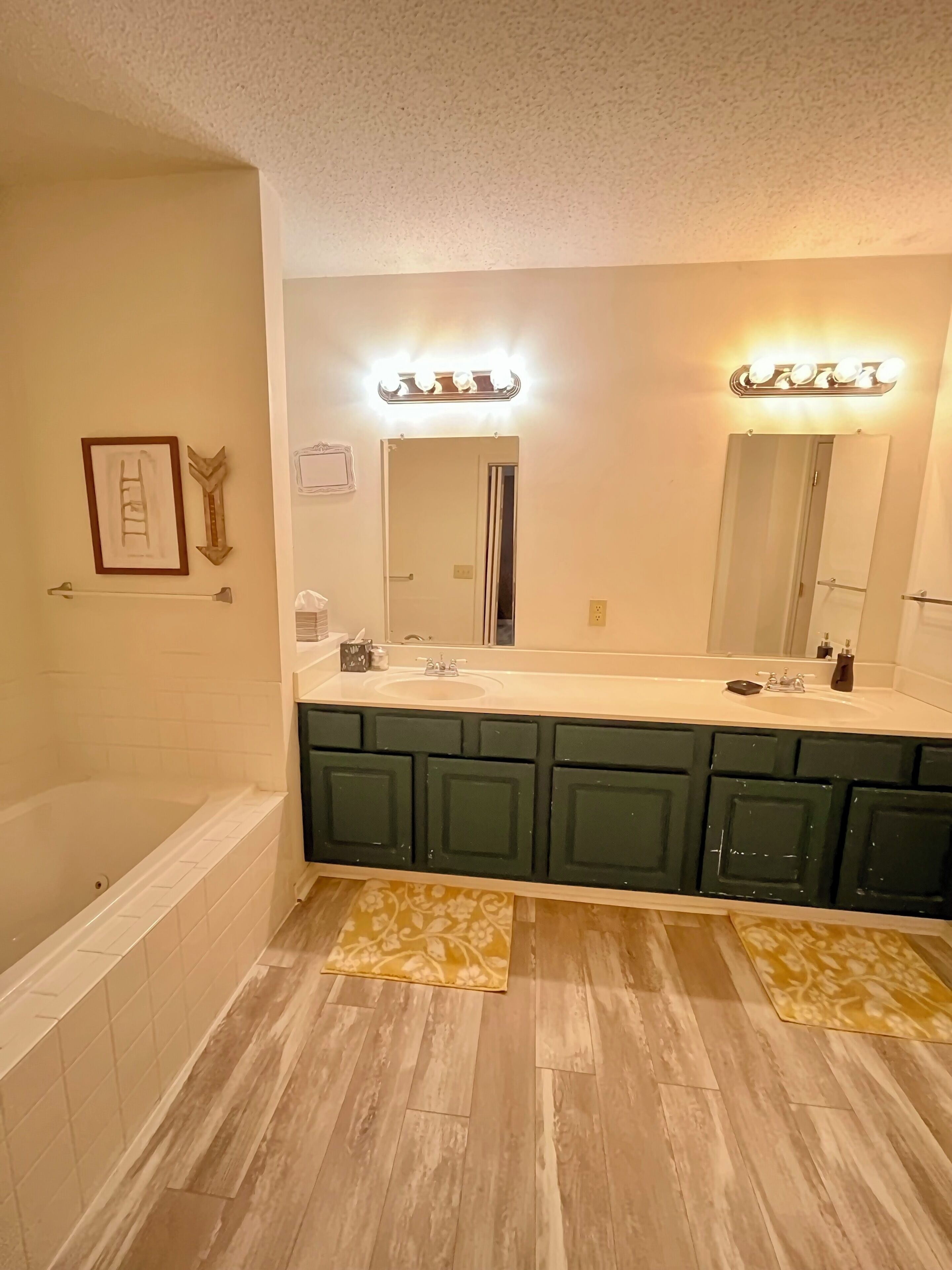 A bathroom with a bathtub, vanity with a mirror, and a lighted vanity area.