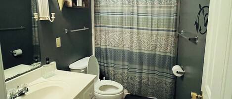 A bathroom with a toilet, sink, mirror, and shower curtain.