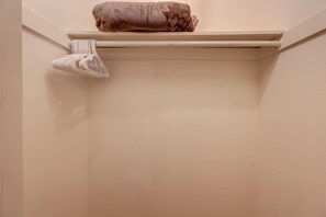 A room with a towel on a shelf and a folded towel on the wall.