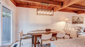 A dining area with a wooden table, white chairs, a chandelier, and a floor lamp.