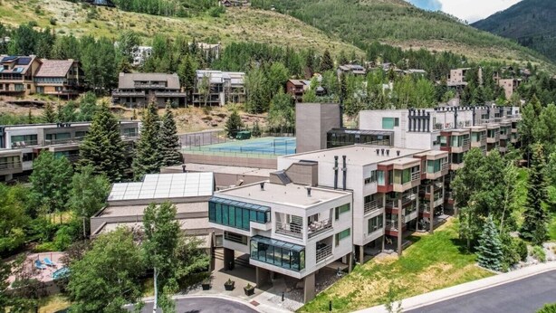 Un complexe résidentiel moderne composé de plusieurs bâtiments, doté d’une piscine et situé dans un cadre montagneux.
