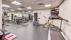 Une salle de sport équipée de tapis de course, de vélos d’exercice et d’appareils de musculation.