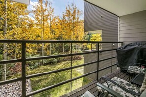 A balcony with a view of a garden and trees, a grill, and outdoor furniture. - Vail Simba Run 2 BR Condo with Resort Facilities (Vail)
