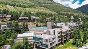 Un moderno barrio residencial con edificios de varios pisos, una piscina y montañas al fondo.