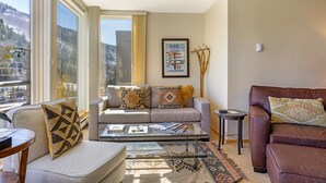 Una sala de estar con sofá, sillón, mesa de centro y un cuadro en la pared.