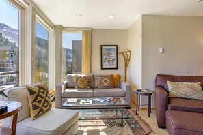 Ein Wohnzimmer mit Sofa, Sessel, Couchtisch und einem gerahmten Bild an der Wand.