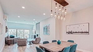 Un intérieur moderne comprenant un coin repas, un espace de vie avec une cheminée et des œuvres d’art accrochées aux murs.