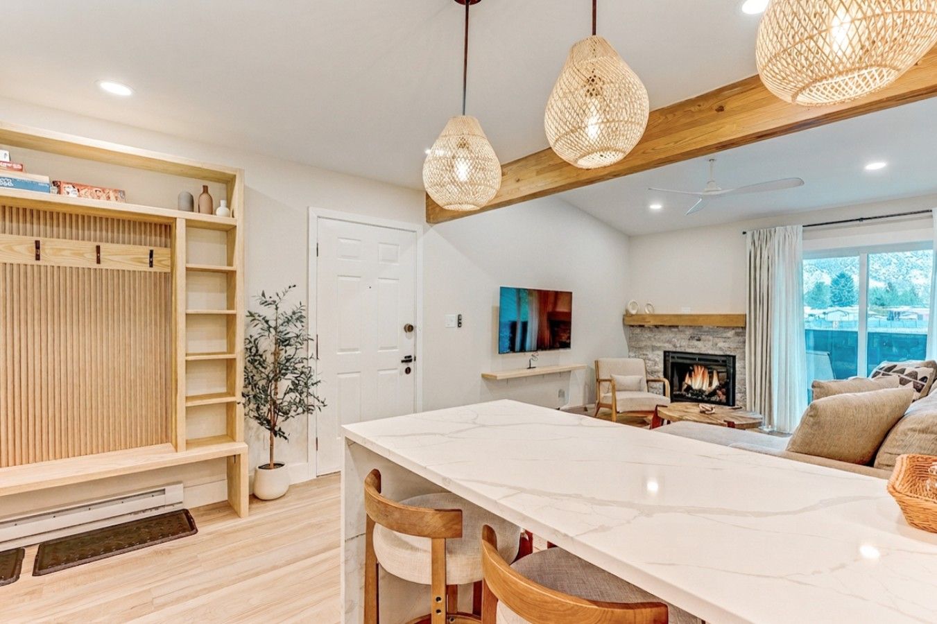 Una sala de estar moderna con chimenea, un comedor con mesa de mármol y techo de madera.