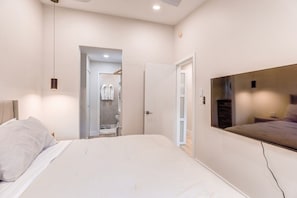 Un dormitorio moderno con una cama grande, un televisor montado en la pared y un vestidor.