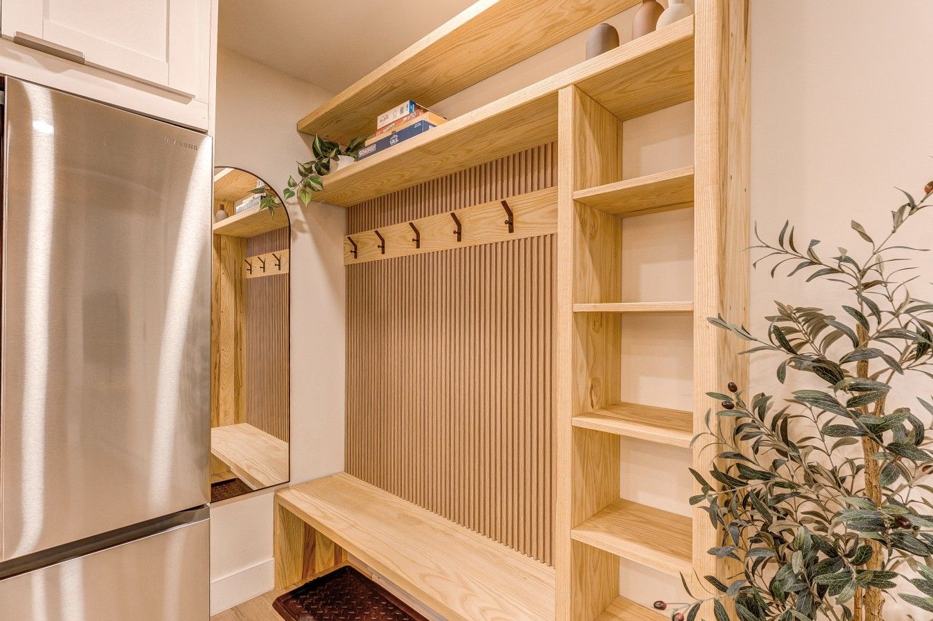 Una cocina moderna con un refrigerador de acero inoxidable, estantes de madera y una planta.
