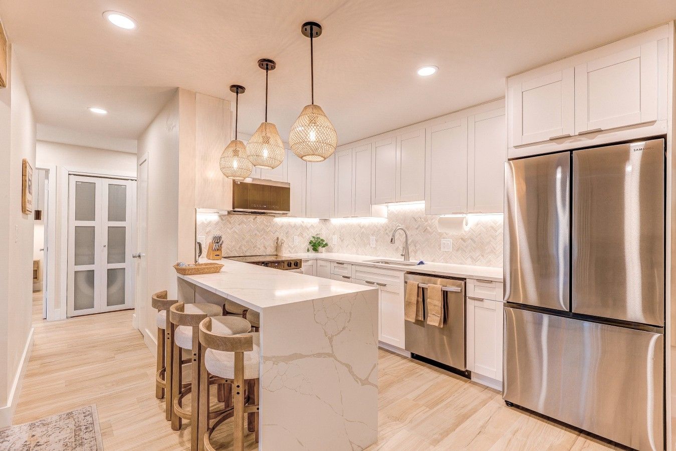 Una cocina moderna con una isla central, electrodomésticos de acero inoxidable e iluminación colgante.