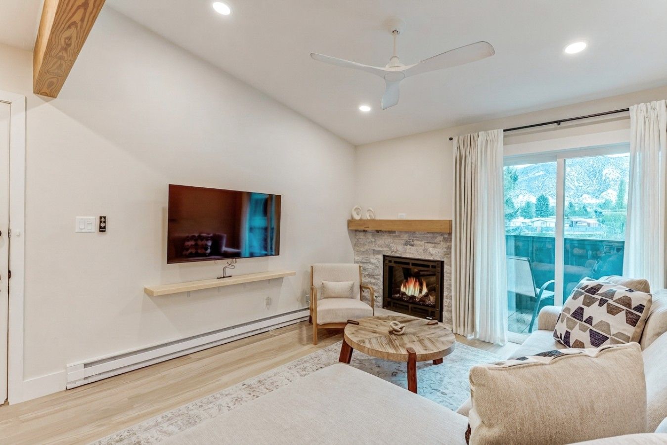 Una sala de estar moderna con una televisión de pantalla plana, chimenea, sofá y mesa de comedor.