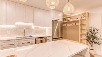 Una cocina moderna con armarios blancos, encimera de mármol y refrigerador integrado.