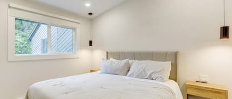 A bedroom with a bed, a nightstand, a ceiling fan, and a window.