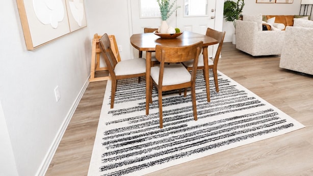A dining area with a wooden table, four chairs, a white rug, and a white door with windows. - Haven on the Hill, Modern 3BR Near Fort Cavazos (Copperas Cove)