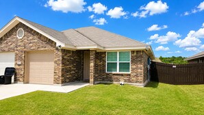 A single-story house with a garage, a brick facade, a window with blinds, and a fenced yard. - Haven on the Hill, Modern 3BR Near Fort Cavazos (Copperas Cove)