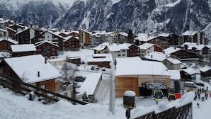 A snow-covered mountain village with chalet-style buildings, a ski lift, and a ski slope. - Dilaila, (Grächen), by Interhome (Grächen)