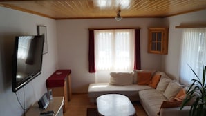 A living room with a sofa, a TV, a small table, and a window with curtains. - Dilaila, (Grächen), by Interhome (Grächen)