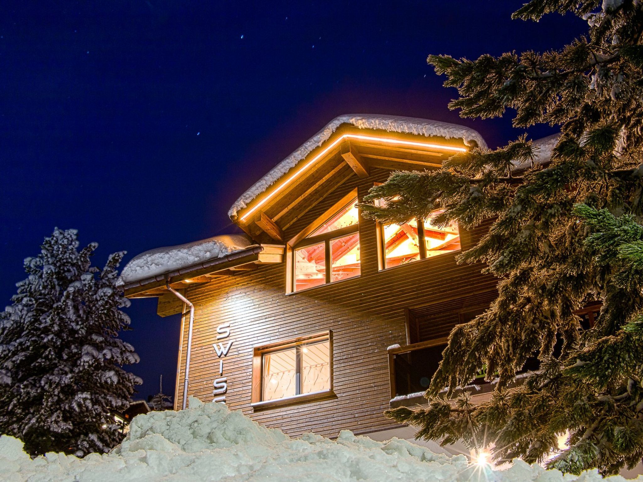 A snow-covered lodge with a visible 'SWISS' sign, indicating a location in Switzerland.