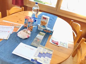 A round wooden table with various items including a water bottle, ice tea cartons, a box of Petit Beurre chocolate, and several brochures. - Swiss, (Grächen), 1066 by Interhome (Grächen)
