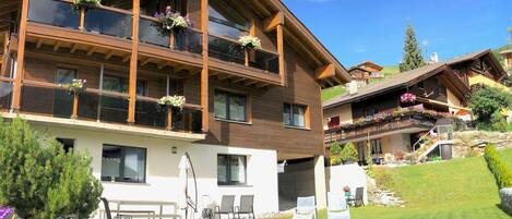 A multi-story building with balconies, a lawn, and outdoor seating.