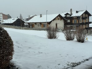 Ein schneebedecktes Wohngebiet mit Häusern, blauem Himmel und einer gut sichtbaren Straße.
